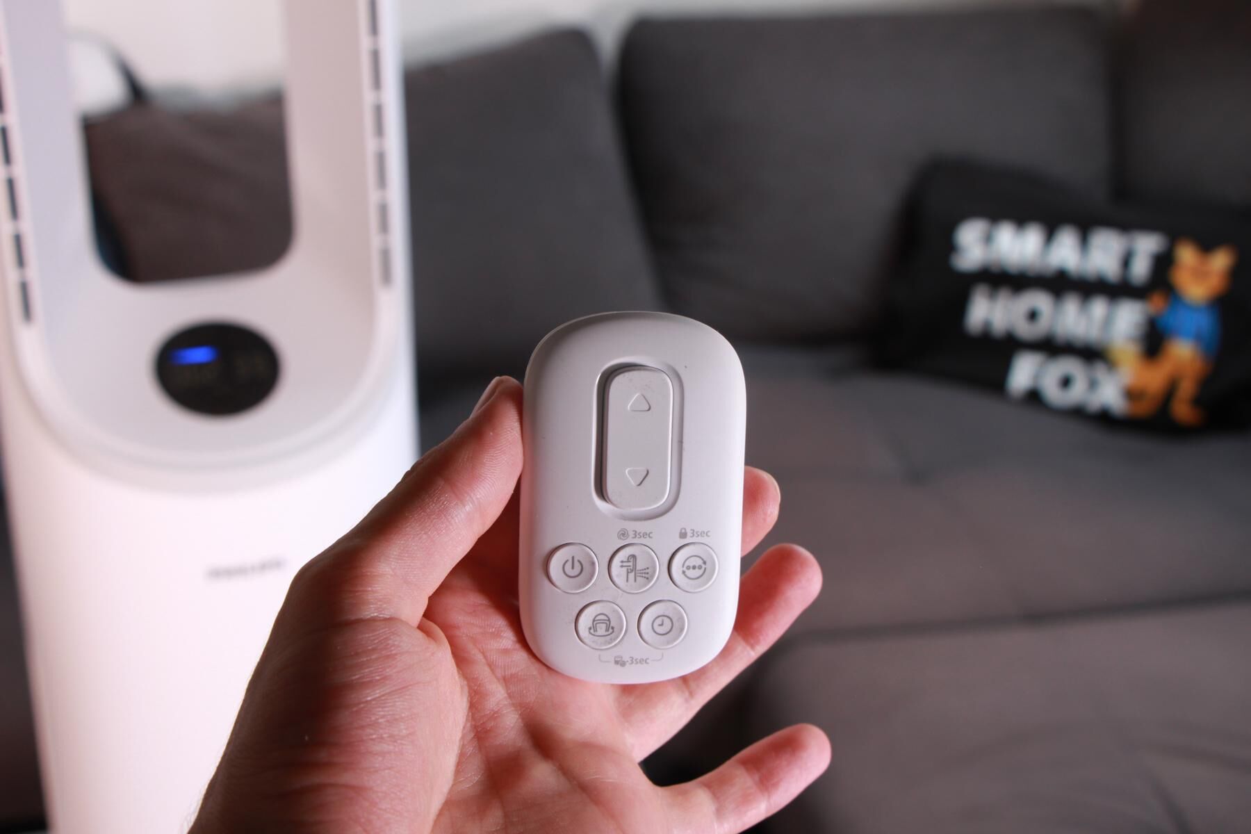 Die Fernbedienung des Philips Air Performer 7000 wird in der Hand vor dem Kombigerät gehalten.